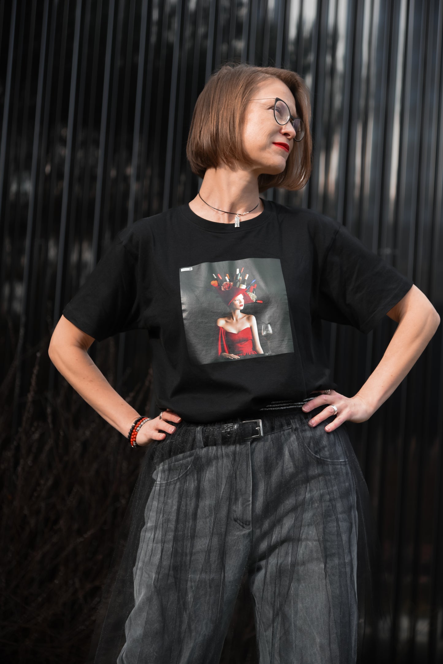 Black unisex T-shirt with AI-generated Hello Weekend print from M2ArtWear, styled with jeans and transparent skirt on a model in Zurich