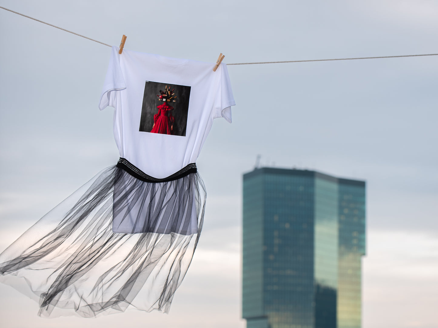 White unisex T-shirt with AI-generated wine couture print from M2ArtWear, styled with transparent skirt, gently blowing in the wind nest to Prime tower in Zurich