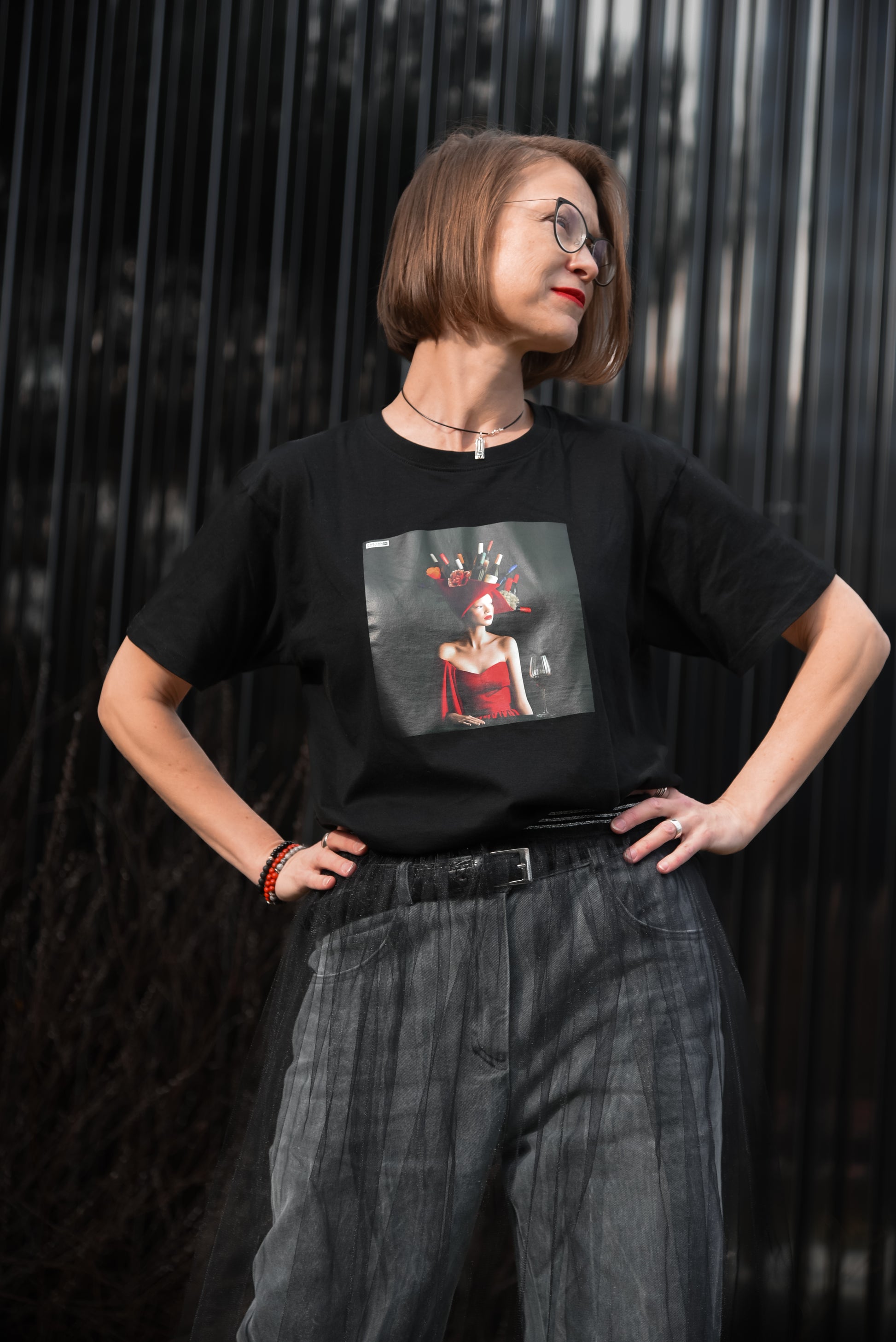 Black unisex T-shirt with AI-generated Hello Weekend print from M2ArtWear, styled with jeans and transparent skirt on a model in Zurich